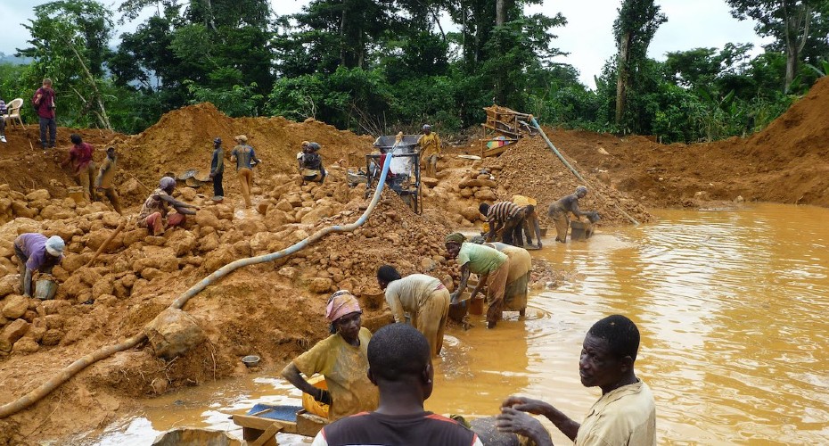 People mining on the bank of a river/water, working by hand